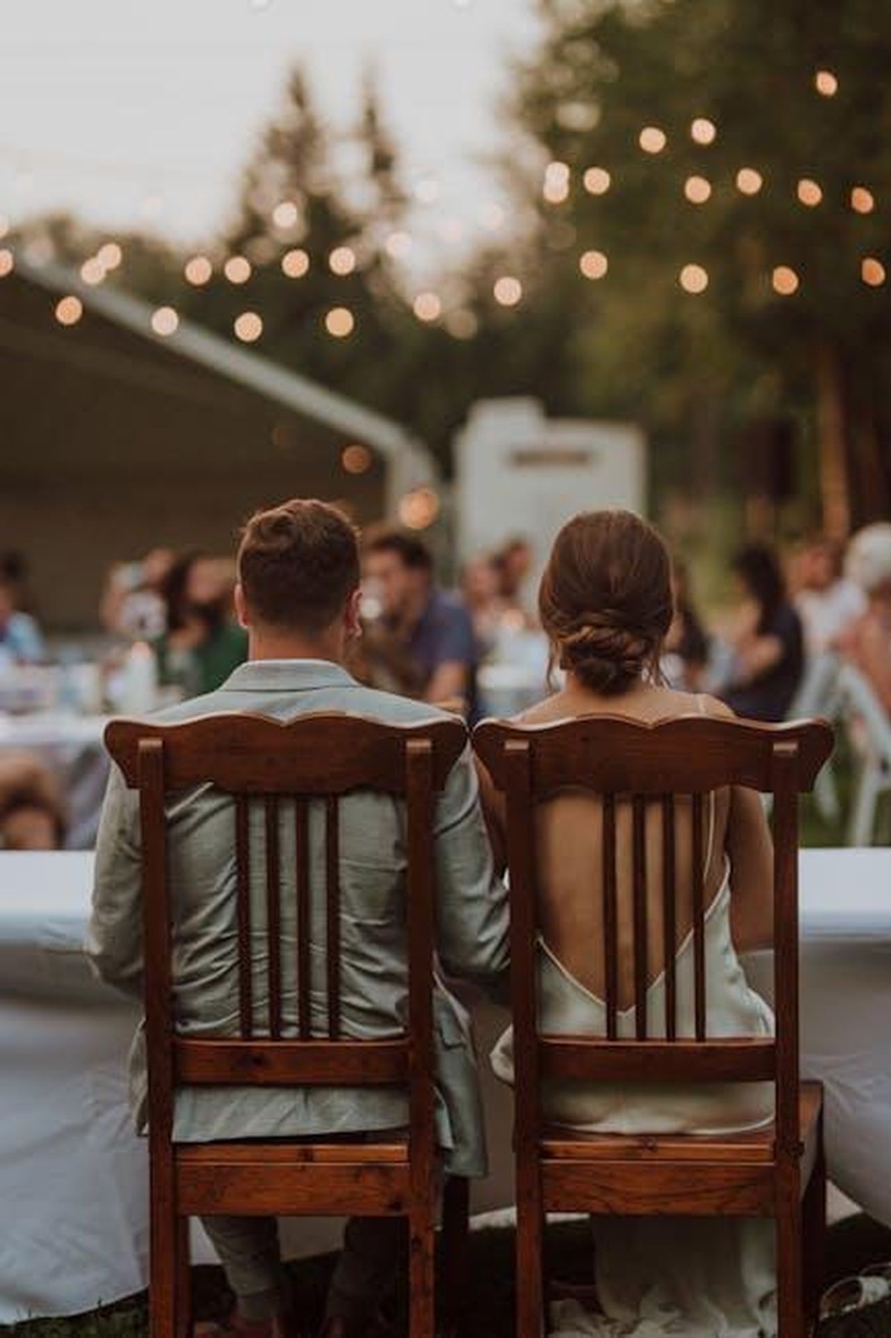 Le_relazioni_recenti_di_Eric_Dane_ECizLgzaIf - Confidenze24 Source: cole peters - pexels - Back view of a couple sitting together at an outdoor wedding reception with warm lighting, creating a romantic ambiance.