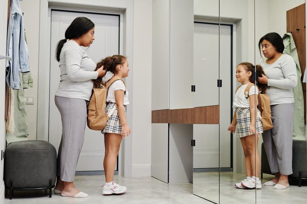 Le_sfide_del_coparenting_8UbiF12LfA - Confidenze24 Source: Tiger Lily - pexels - A mother and daughter preparing for school in front of a mirror, showcasing morning routines.