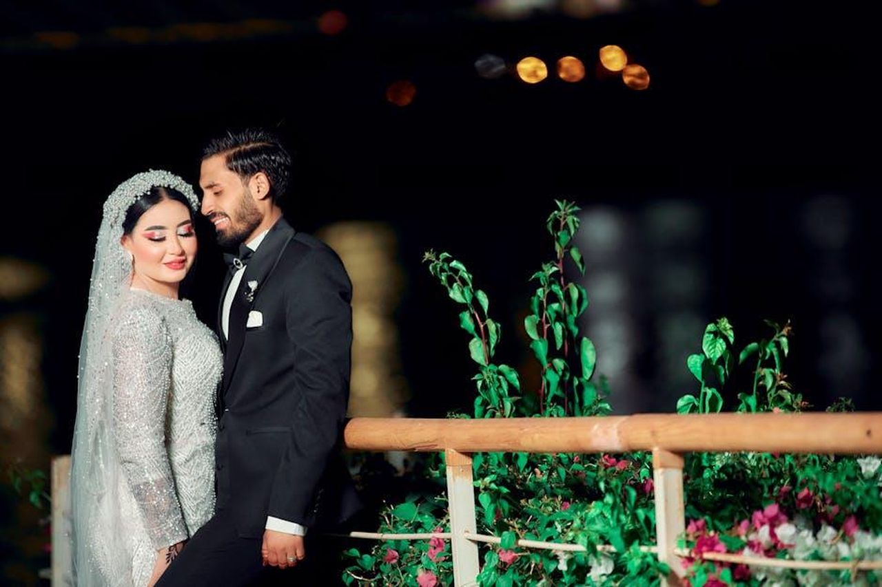 Le_speculazioni_sulla_relazione_di_Grohl_e_Blum_w51cQBfQeF - Confidenze24 Source: taha alnagar official - pexels - A couple embraces in wedding attire by a waterfront at night, showcasing elegance and romance.