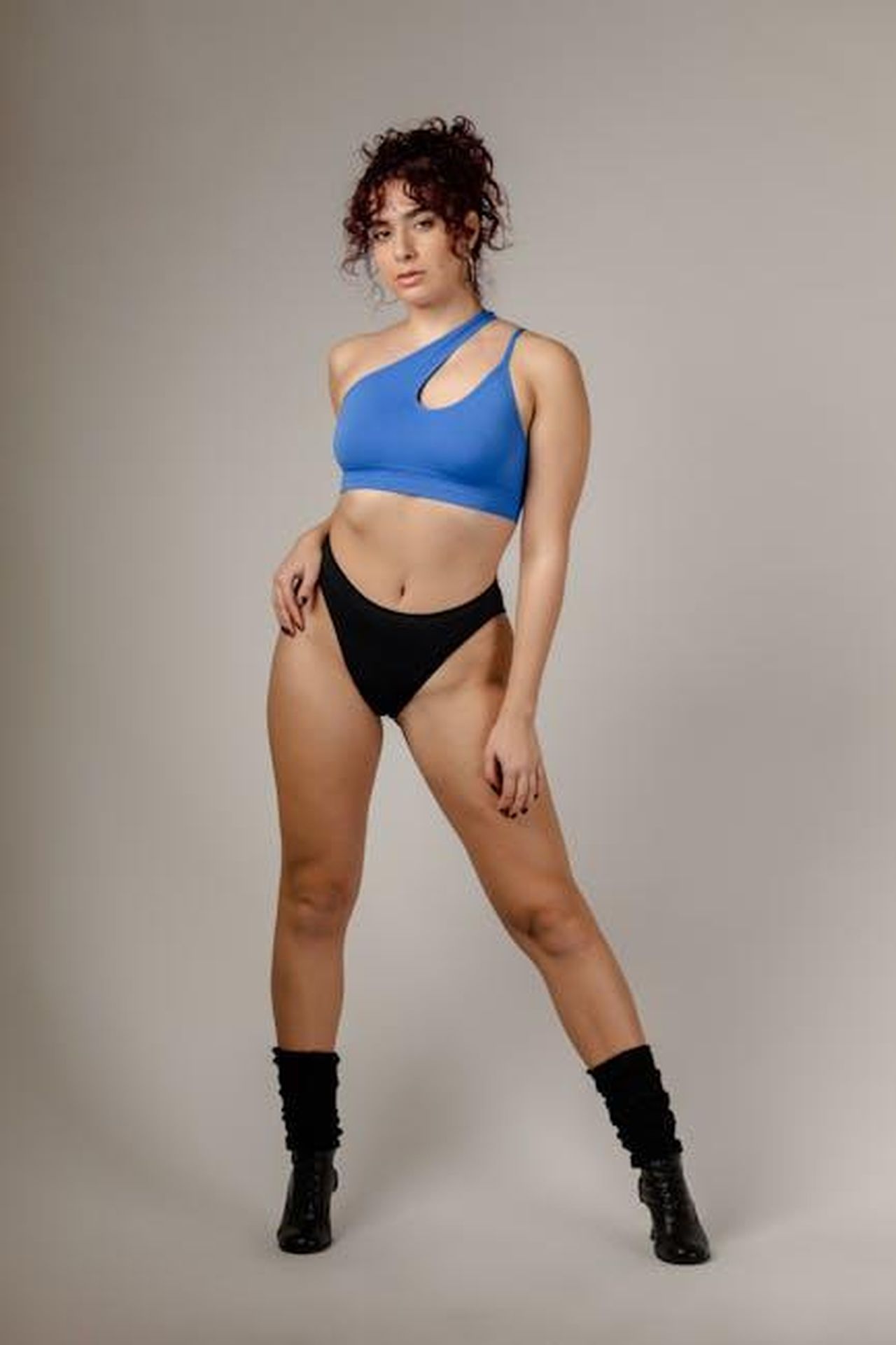 Leggings_e_jeans_Spanx_musthave_per_ogni_guardaroba_Cpo4VtoV94 - Confidenze24 Source: Lazarus Ziridis - pexels - Woman posing confidently in blue sports top and black shorts against a neutral background.