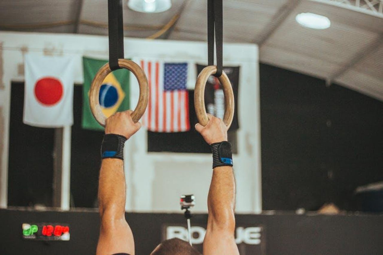 Lentusiasmo_di_Luna_per_la_ginnastica_QASO64uAnw - Confidenze24 Source: Victor Freitas - pexels - A gymnast performs on rings indoors, showcasing strength and skill.