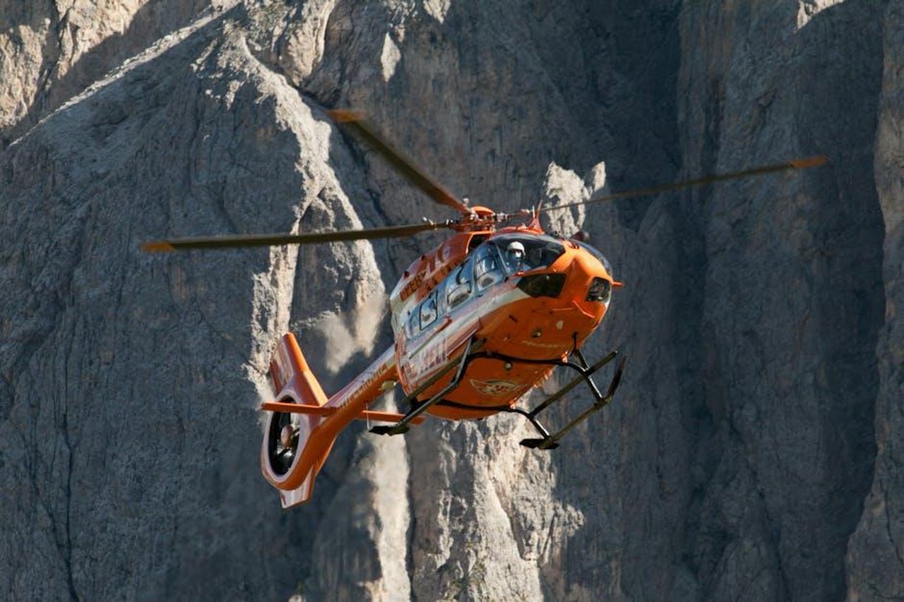 Leone_23_LUGLIO__22_AGOSTO_ghTZeAIgVU - Confidenze24 Source: mark soetebier - pexels - A bright orange rescue helicopter flying amidst the rugged Dolomites mountains.