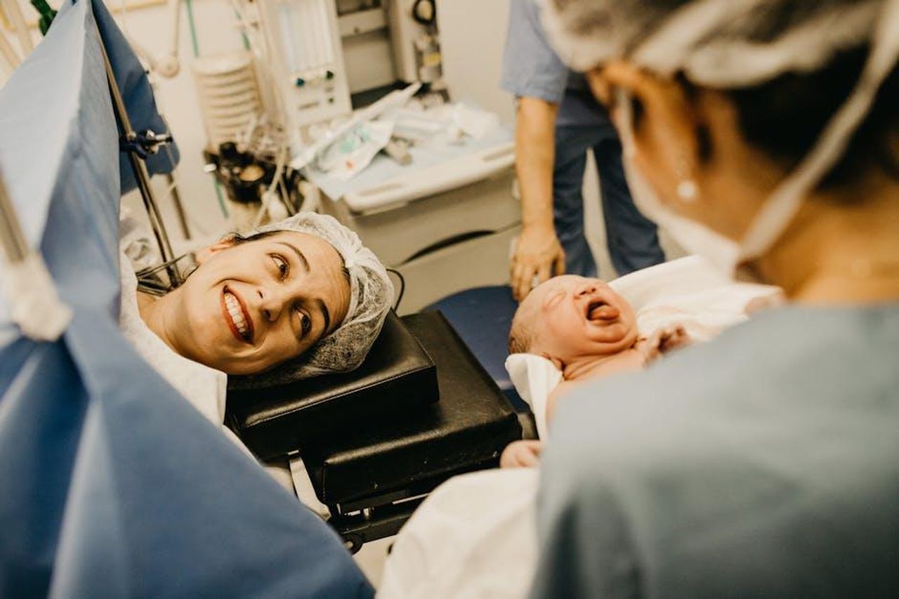 Lesperienza_di_Kylie_durante_i_parti_precedenti_CJd6gw8Yj5 - Confidenze24 Source: Jonathan Borba - pexels - A mother smiles lovingly at her newborn in a hospital delivery room, attended by medical staff.