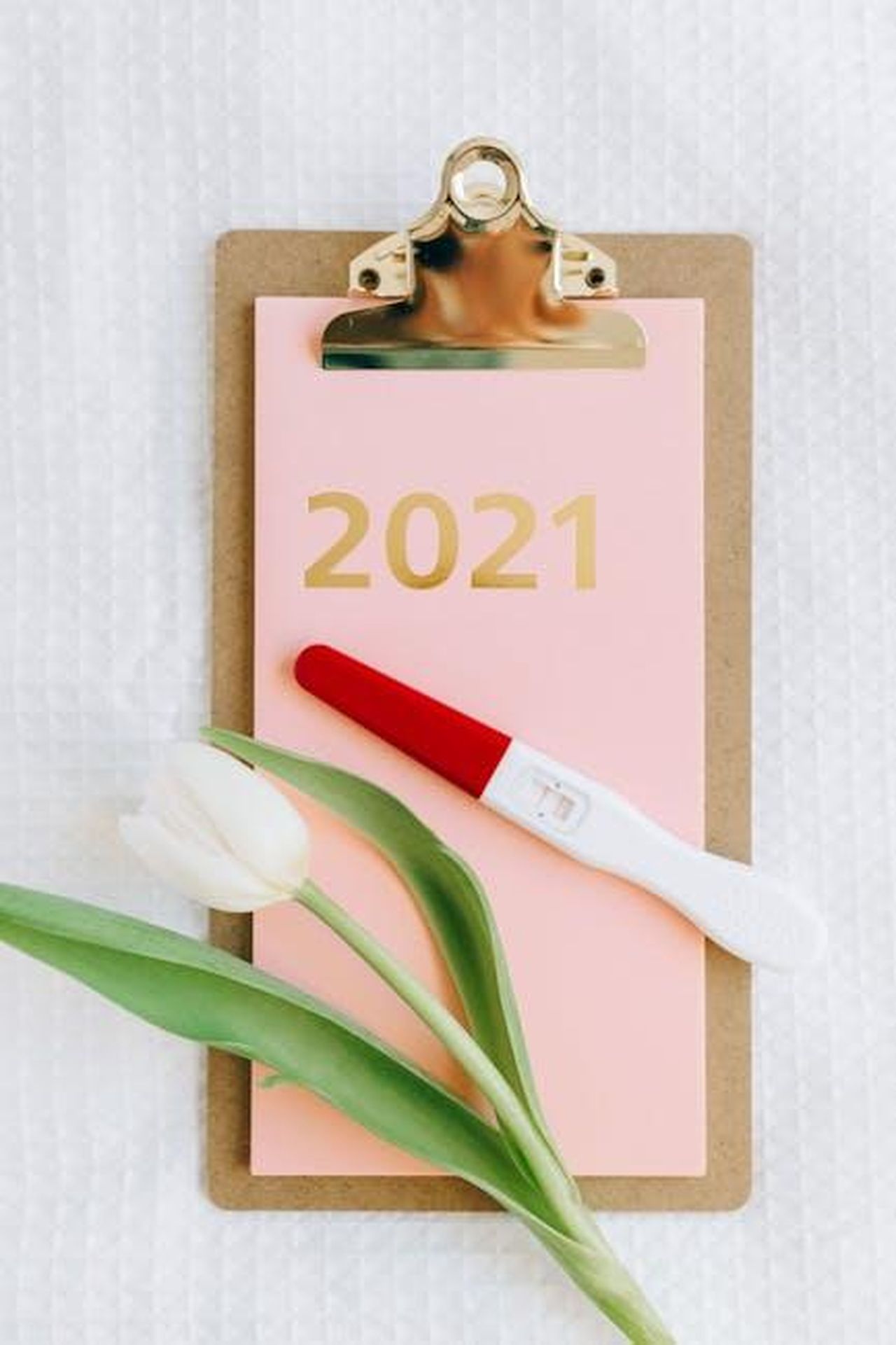 Lestetica_mob_wife_come_ottenerla_lXJ16DzFr7 - Confidenze24 Source: Nataliya Vaitkevich - pexels - Flat lay of a pregnancy test and tulip on a clipboard with 2021 text.