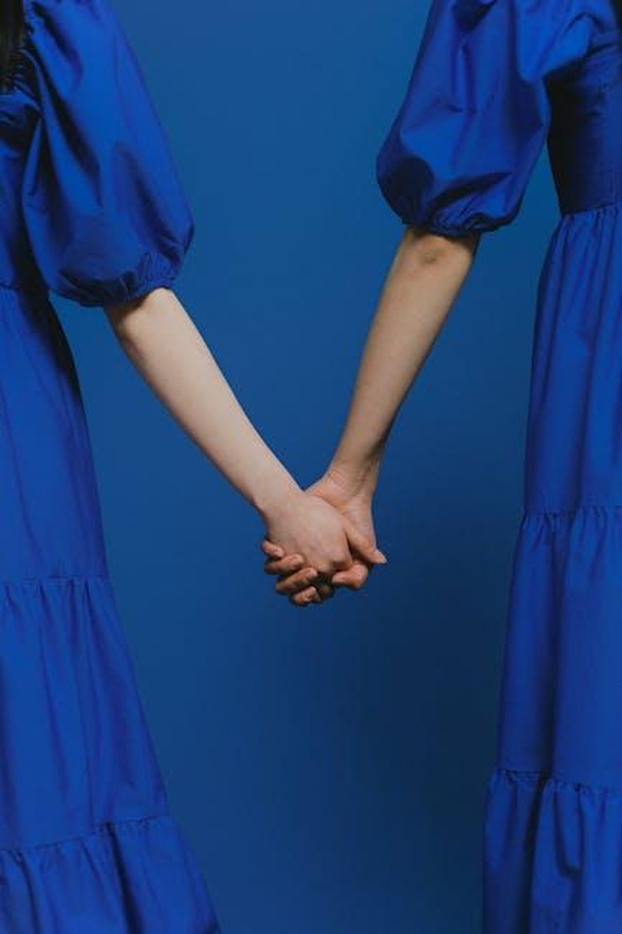 Limportanza_degli_intimacy_coordinators_nel_cinema_moderno_bHTRoJqQKA - Confidenze24 Source: SHVETS production - pexels - Two individuals in blue dresses holding hands against a blue background.