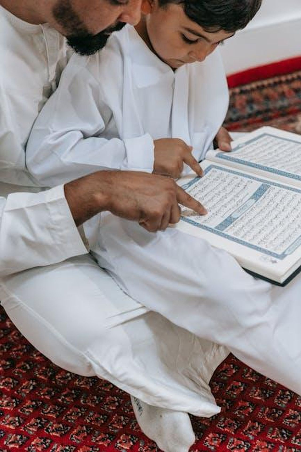 Limportanza_del_rispetto_e_del_consenso_nella_crescita_dei_figli_5nn047fYMl - Confidenze24 Source: Timur Weber - pexels - A father and son reading the Quran together, symbolizing faith and tradition.
