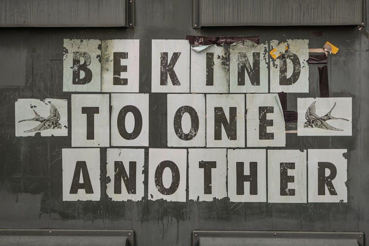 Limportanza_della_consapevolezza_sociale_OLeBbBC5vo - Confidenze24 Source: James Frid - pexels - Close-up of 'Be Kind to One Another' message on a weathered background.