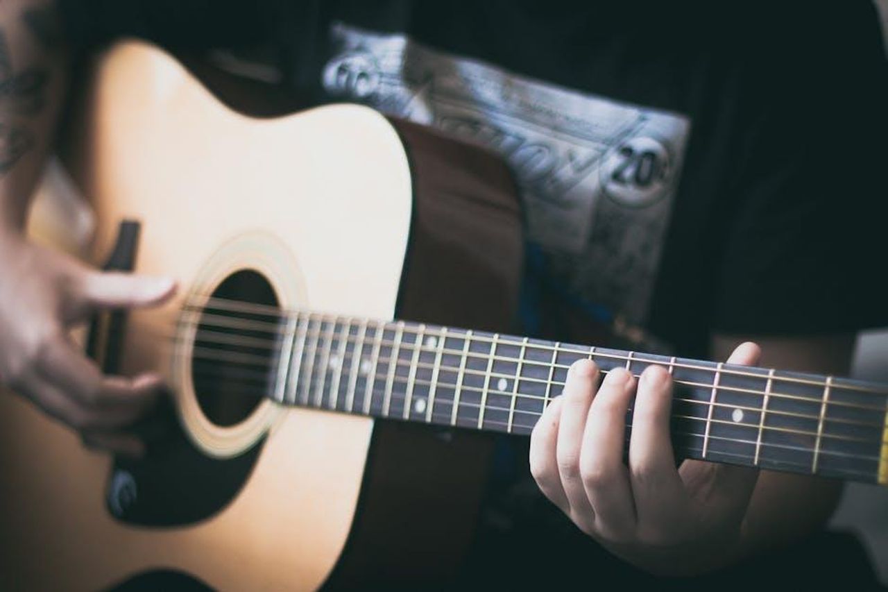 Limportanza_della_performance_per_Doechii_nYpu6QfnaW - Confidenze24 Source: Thomas Casas - pexels - A person playing an acoustic guitar, focusing on guitar strings.