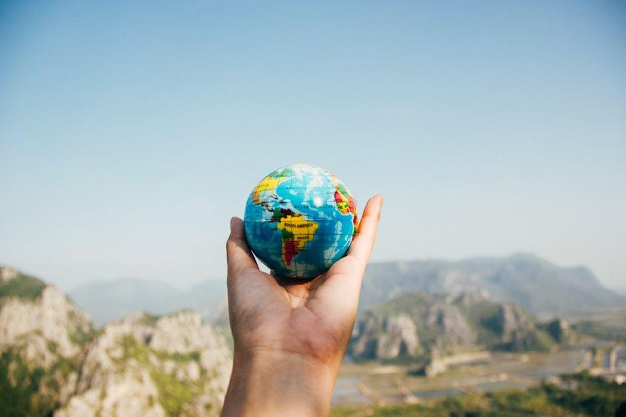 Limportanza_dellassicurazione_di_viaggio_wicXXT685L - Confidenze24 Source: Porapak Apichodilok - pexels - Hand holding a globe against a mountain background symbolizing travel and exploration.