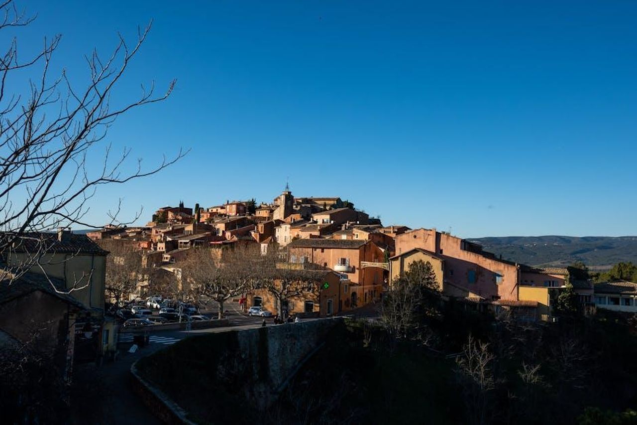 Limportanza_delle_piccole_citt_per_le_loro_figlie_V9jWIb6bwA - Confidenze24 Source: Bingqian Li - pexels - Picturesque view of Roussillon village in Provence with traditional ochre-colored buildings under a clear blue sky.