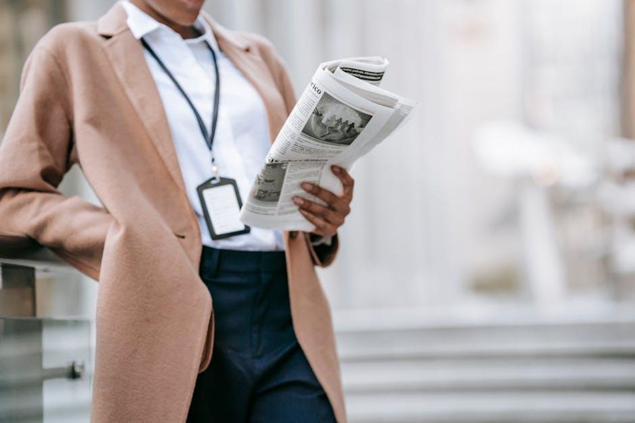 Limportanza_di_un_uso_equilibrato_dei_media_x21rSGvIN7 - Confidenze24 Source: Ono Kosuki - pexels - Crop unrecognizable young African American female entrepreneur in elegant brown coat with badge reading newspaper while leaning on railing near stairs