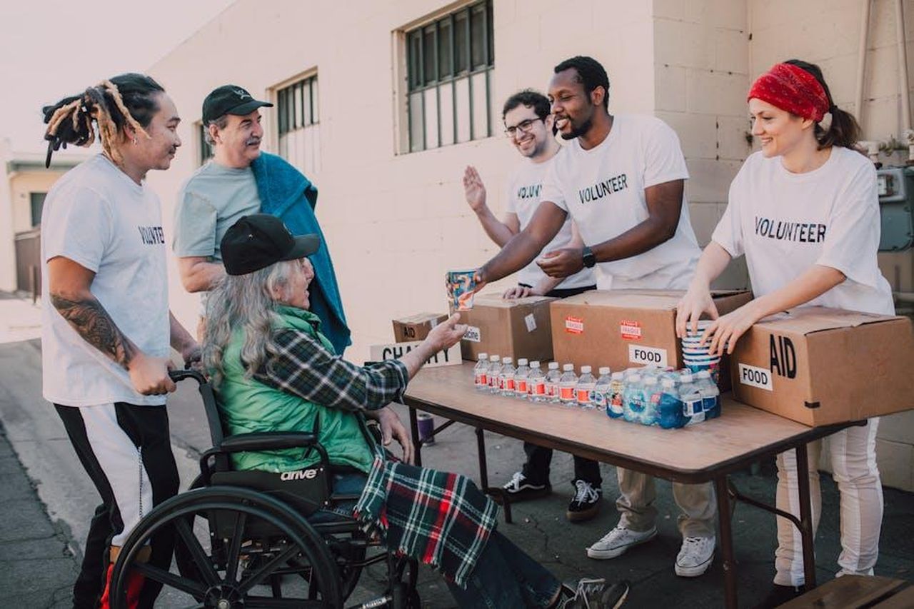 Linfluenza_di_Taylor_Swift_sulla_filantropia_di_Kelce_KunE03cd8e - Confidenze24 Source: RDNE Stock project - pexels - Volunteers distribute bottled water and supplies to diverse individuals in an outdoor setting, showcasing community support.