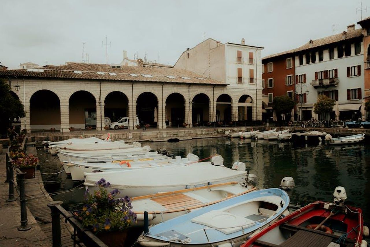 Lispirazione_di_Demi_Moore_RHJdA3ckc8 - Confidenze24 Source: Marcel Gierschick - pexels - A picturesque view of boats moored along an Italian harbor with historical buildings in the background.