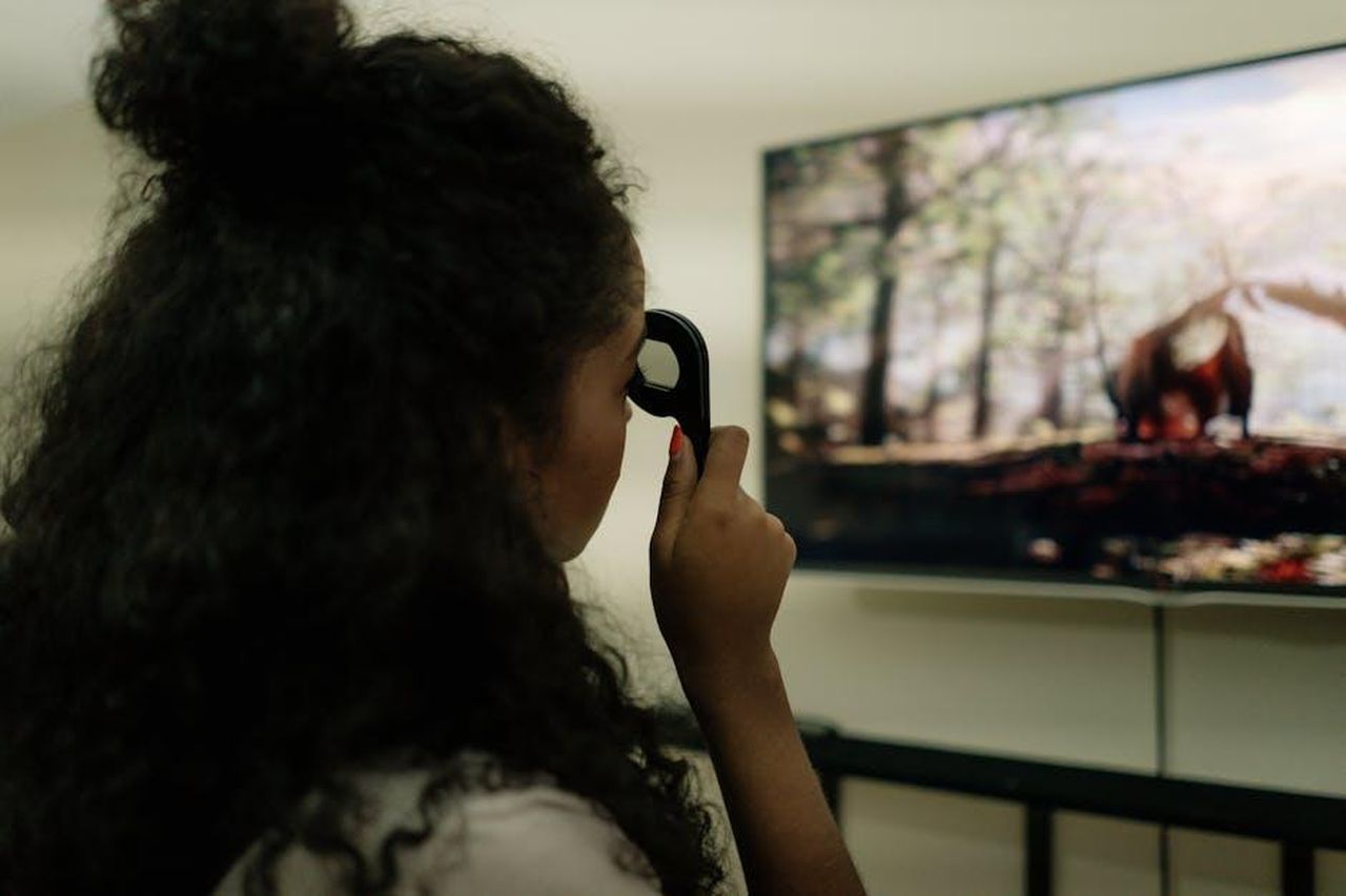 Lorraine_Kelly_affronta_largomento_offensivo_di_Vernon_wAw6Bdh7n4 - Confidenze24 Source: cottonbro studio - pexels - A woman with curly hair using a remote control to watch a nature documentary on a flat-screen TV indoors.