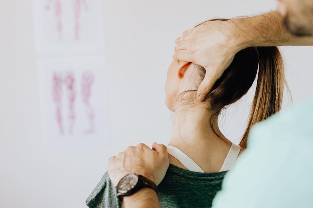 Lotta_con_lalcol_e_riabilitazione_DlXjnm6s9a - Confidenze24 Source: Photo By: Kaboompics.com - pexels - Back view of crop faceless bearded orthopedist in wristwatch checking up neck of anonymous lady while standing in front of wall with paper drawings representing body anatomy