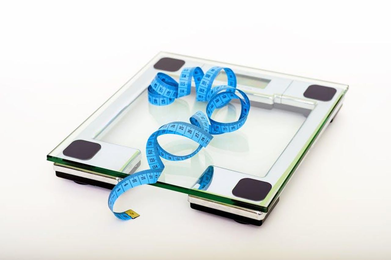 Louise_parla_dellaumento_di_peso_dovuto_ai_farmaci_EEmDjPT7bZ - Confidenze24 Source: Pixabay - pexels - A digital glass weighing scale with a blue measuring tape, symbolizing weight management.