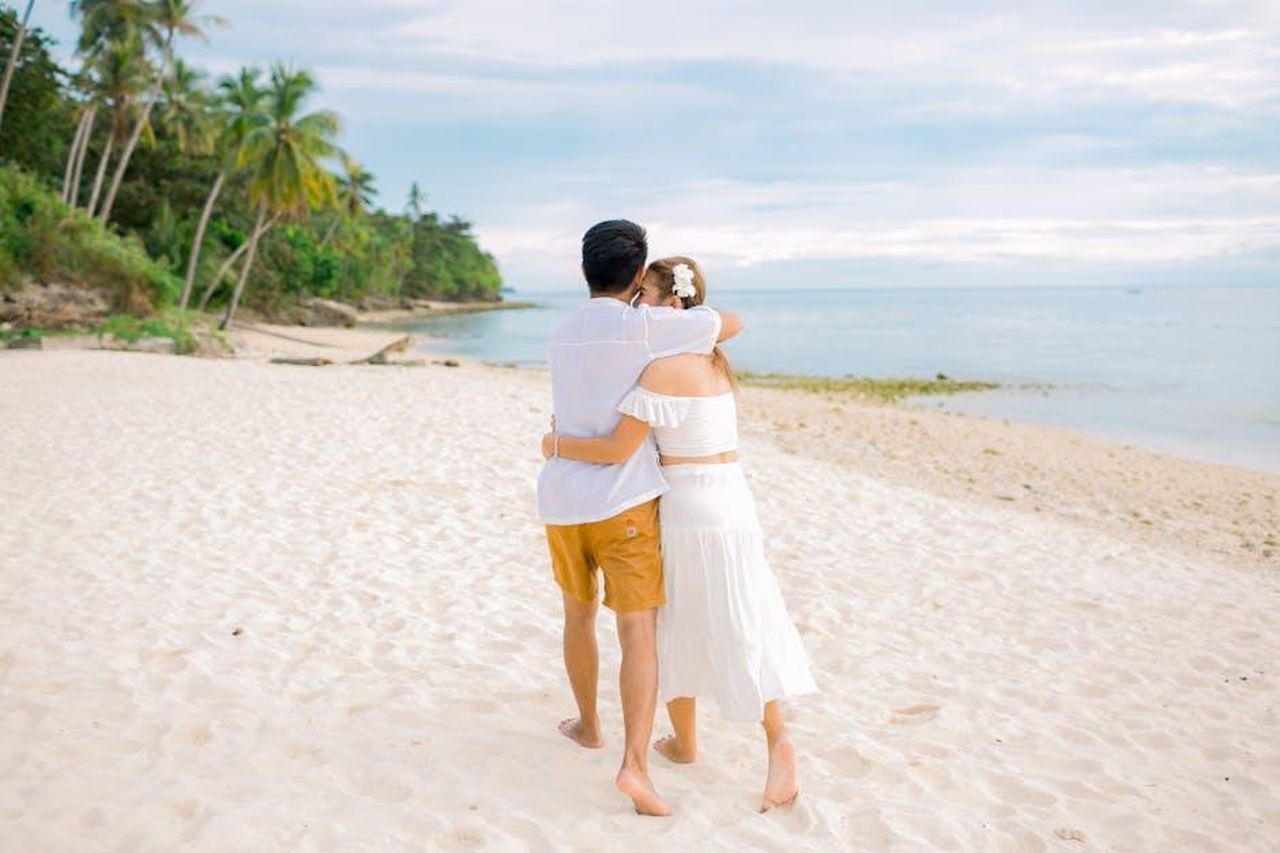 Lultimatum_di_John_Miller_a_Jennifer_Garner_BusCCjGkUA - Confidenze24 Source: Dax Dexter Delada - pexels - A couple embracing while walking together on a serene tropical beach under a clear sky.