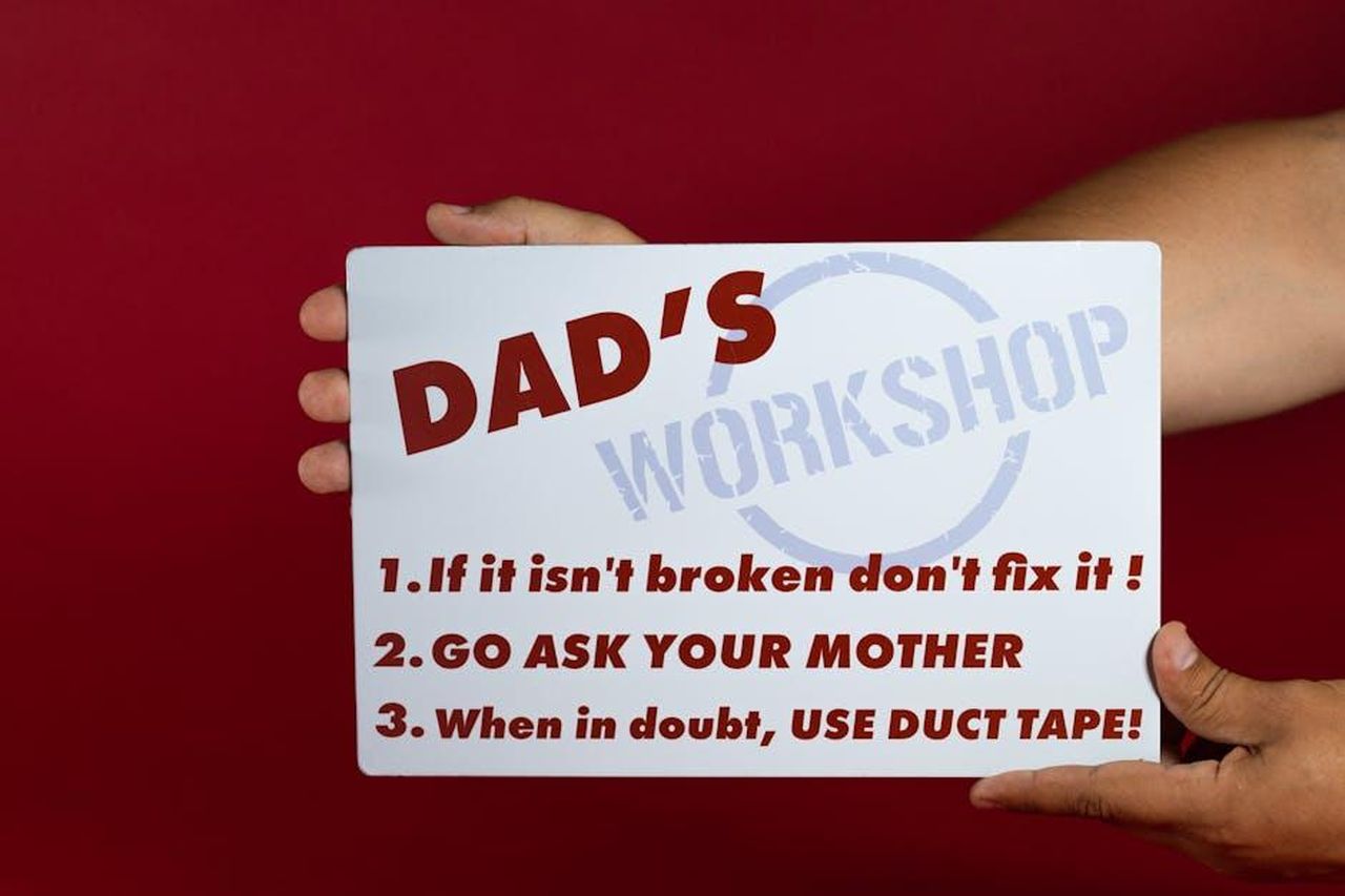 Lumorismo_inappropriato_dei_figli_e_le_preoccupazioni_dei_genitori_3huUws9d6h - Confidenze24 Source: RDNE Stock project - pexels - Close-up of a humorous sign with Dad's workshop rules on a red background held by hands.