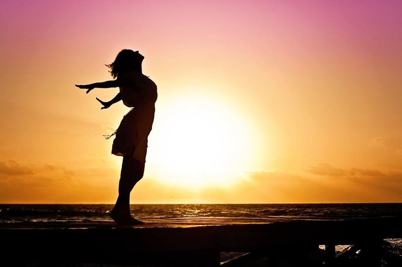 Mai_voluto_interpretare_donne_deboli_ww9UgFpf6D - Confidenze24 Source: Jill Wellington - pexels - Silhouette of a woman at the beach with arms outstretched against a vibrant sunset backdrop.