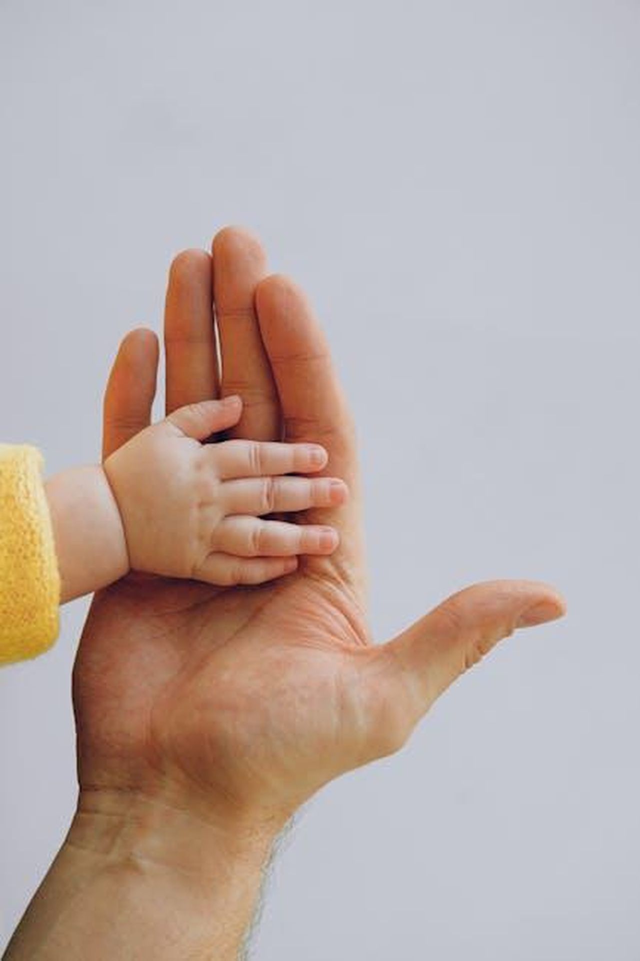 Mark_descrive_la_figlia_come_il_pi_grande_traguardo_della_mia_vita_Jvx3SxlS0a - Confidenze24 Source: Anna Shvets - pexels - Crop anonymous baby in warm wear holding hand on palm of crop parent while standing against white background in studio