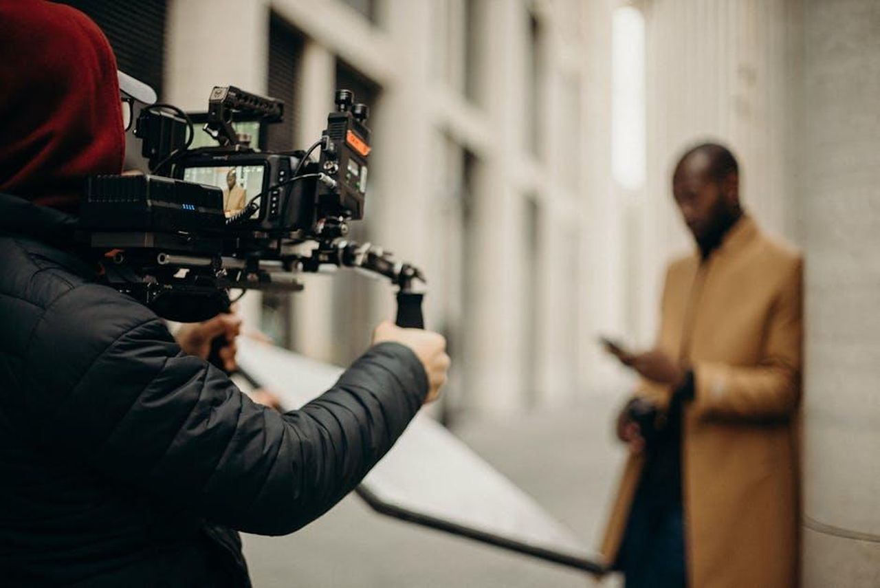 Martin_Henderson_e_Alexandra_Breckenridge_anticipano_la_Stagione_7_681d516rQh - Confidenze24 Source: cottonbro studio - pexels - Cinematic scene of a filmmaker using camera rig outdoors, capturing a stylish male subject.