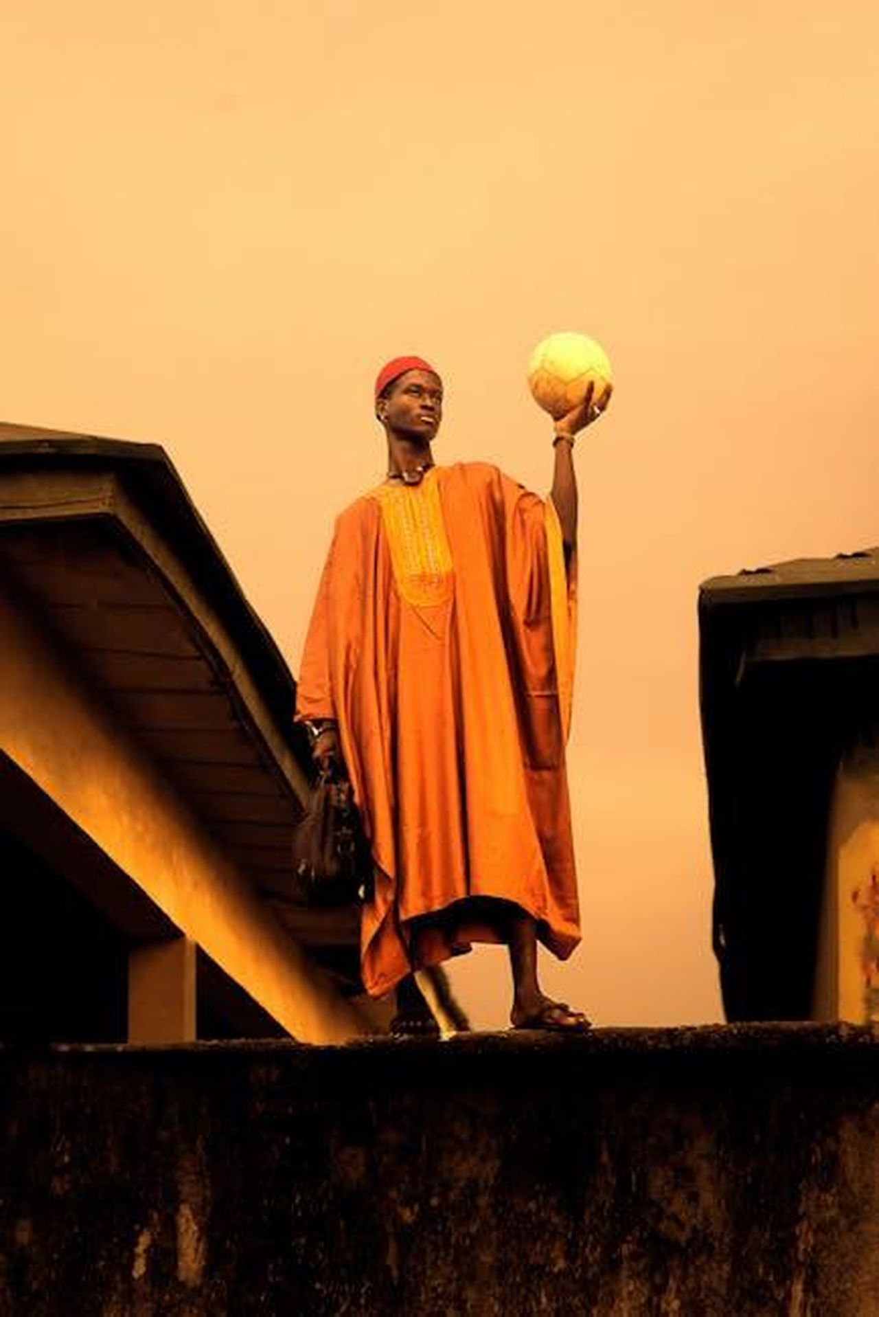 Maya_e_Micah_si_scontrano_xHjSGWM1uZ - Confidenze24 Source: Ario Stories - pexels - Man in traditional garment holding a ball, silhouetted against a sunset sky.