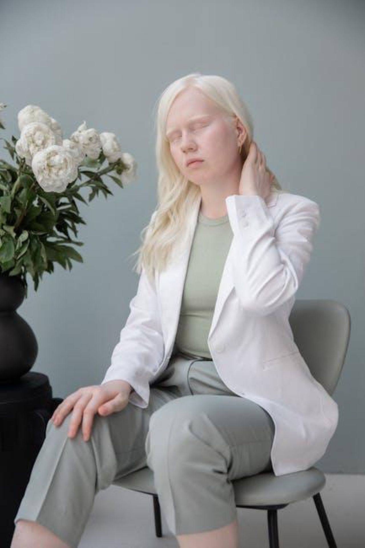Meghan_celebra_la_Giornata_Internazionale_della_Donna_6xG9J5beD6 - Confidenze24 Source: Monstera Production - pexels - Disappointed young female with closed eyes touching neck while sitting on chair near white blooming flowers