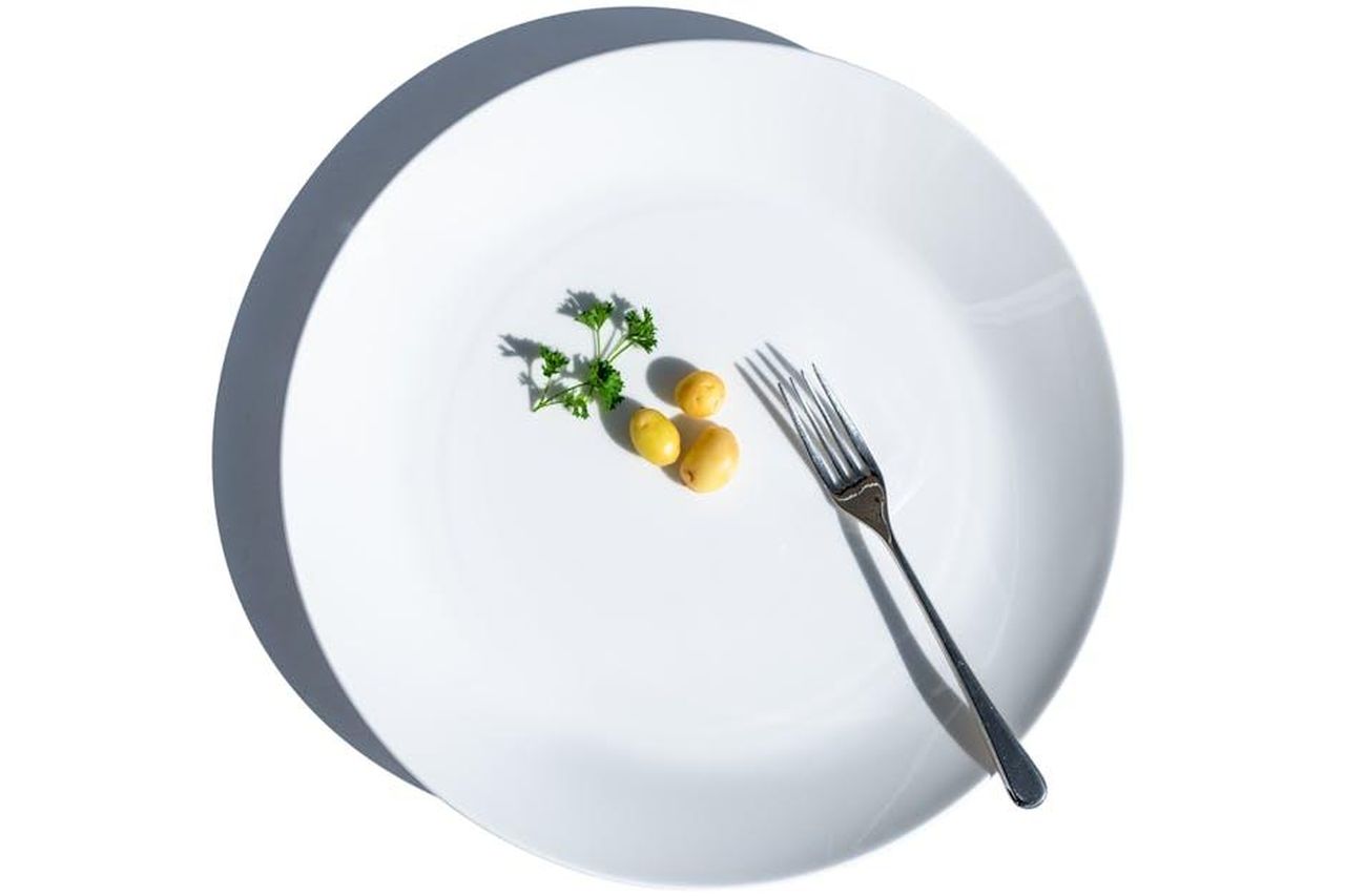 Mettiamo_cos_tanta_pressione_su_noi_stessi_E4j2g3FvUd - Confidenze24 Source: Frank Schrader - pexels - Minimalist still life of potatoes and parsley on a white plate with fork, symbolizing dieting.