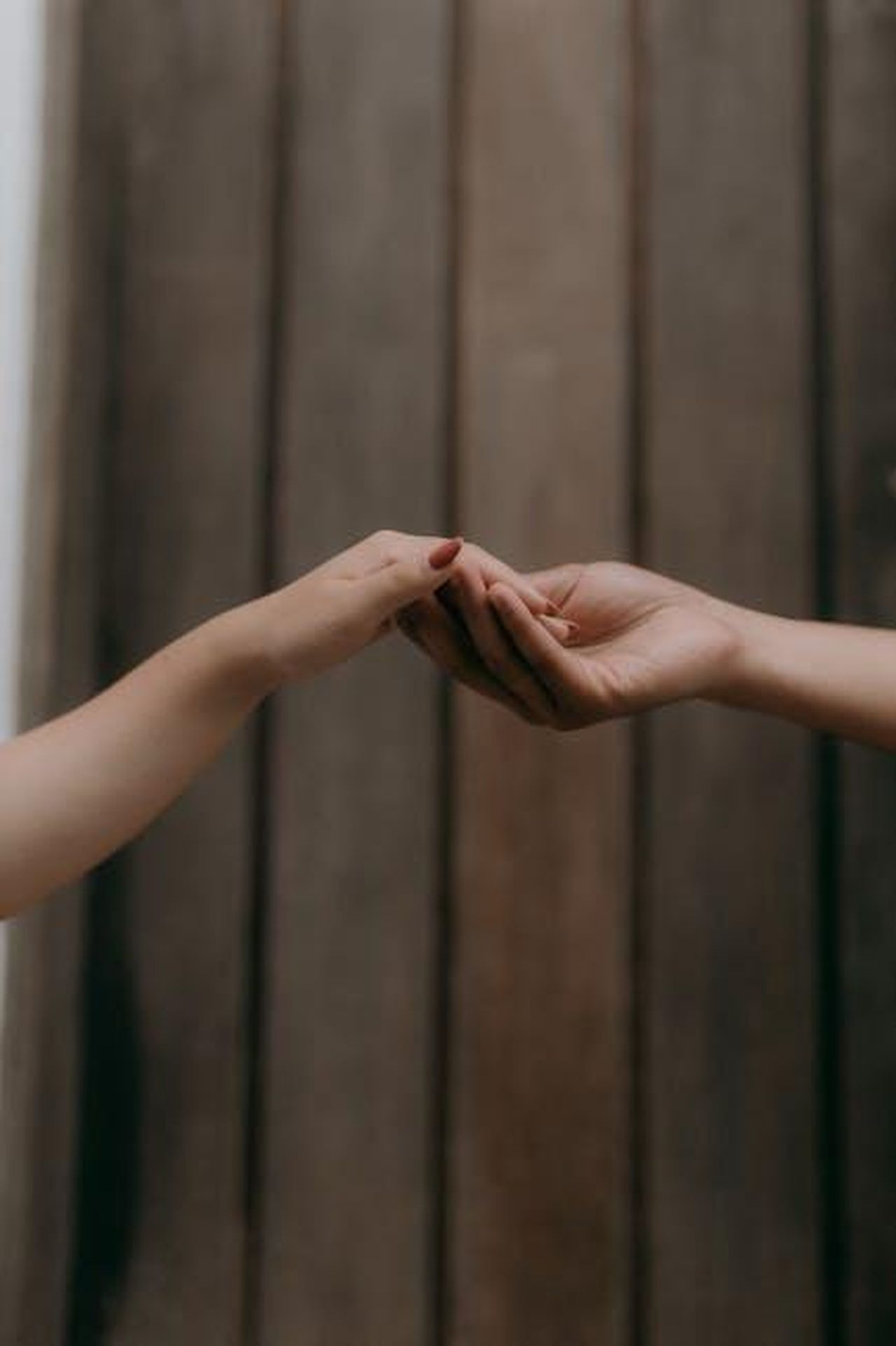Mi_hai_commosso_fino_alle_lacrime_J20Y9aKPz4 - Confidenze24 Source: Alexander Mass - pexels - Minimalist image of two hands softly reaching out to each other against a wooden background.