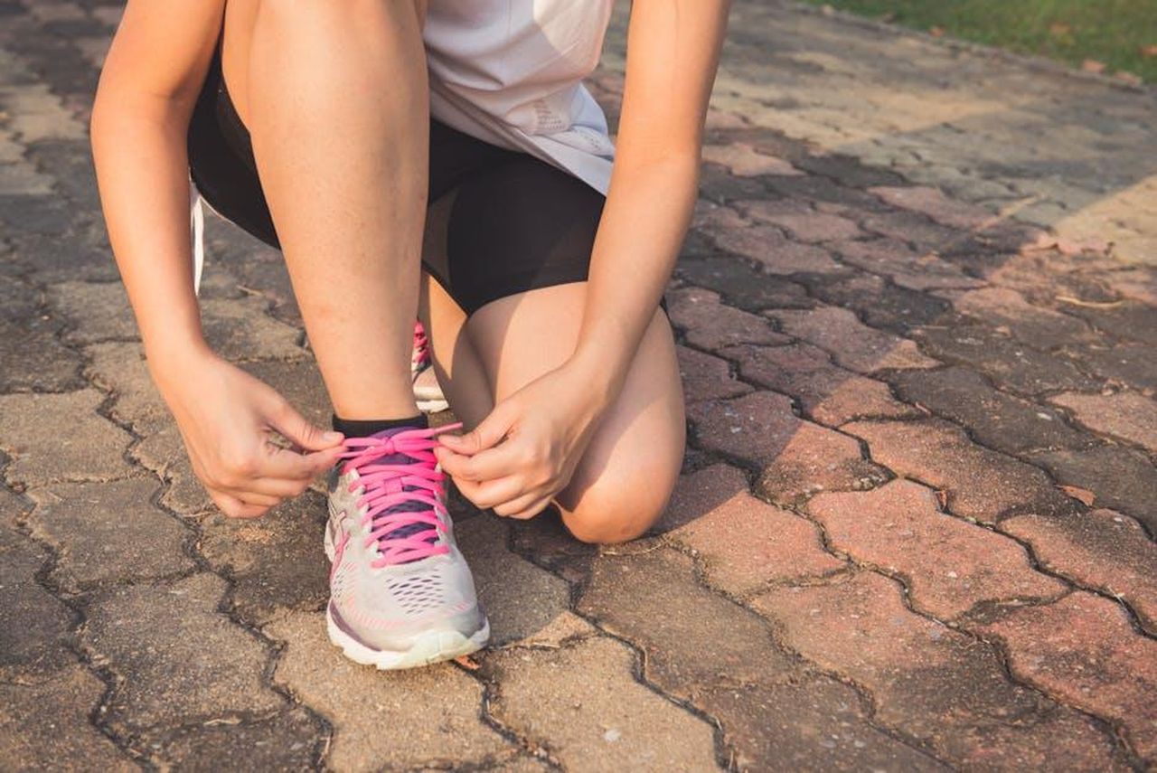 Migliori_offerte_di_scarpe_On_Running_primavera_2025_24QCJ4KGZn - Confidenze24 Source: Tirachard Kumtanom - pexels - Adult woman tying pink laces on running shoes outdoors. Focuses on fitness and lifestyle.