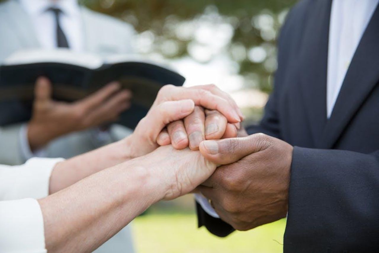 Miller__vicino_ai_figli_di_Garner_8D3YZu9U6K - Confidenze24 Source: Kampus Production - pexels - Interracial couple holding hands during an outdoor wedding ceremony in Portugal, showcasing unity and love.