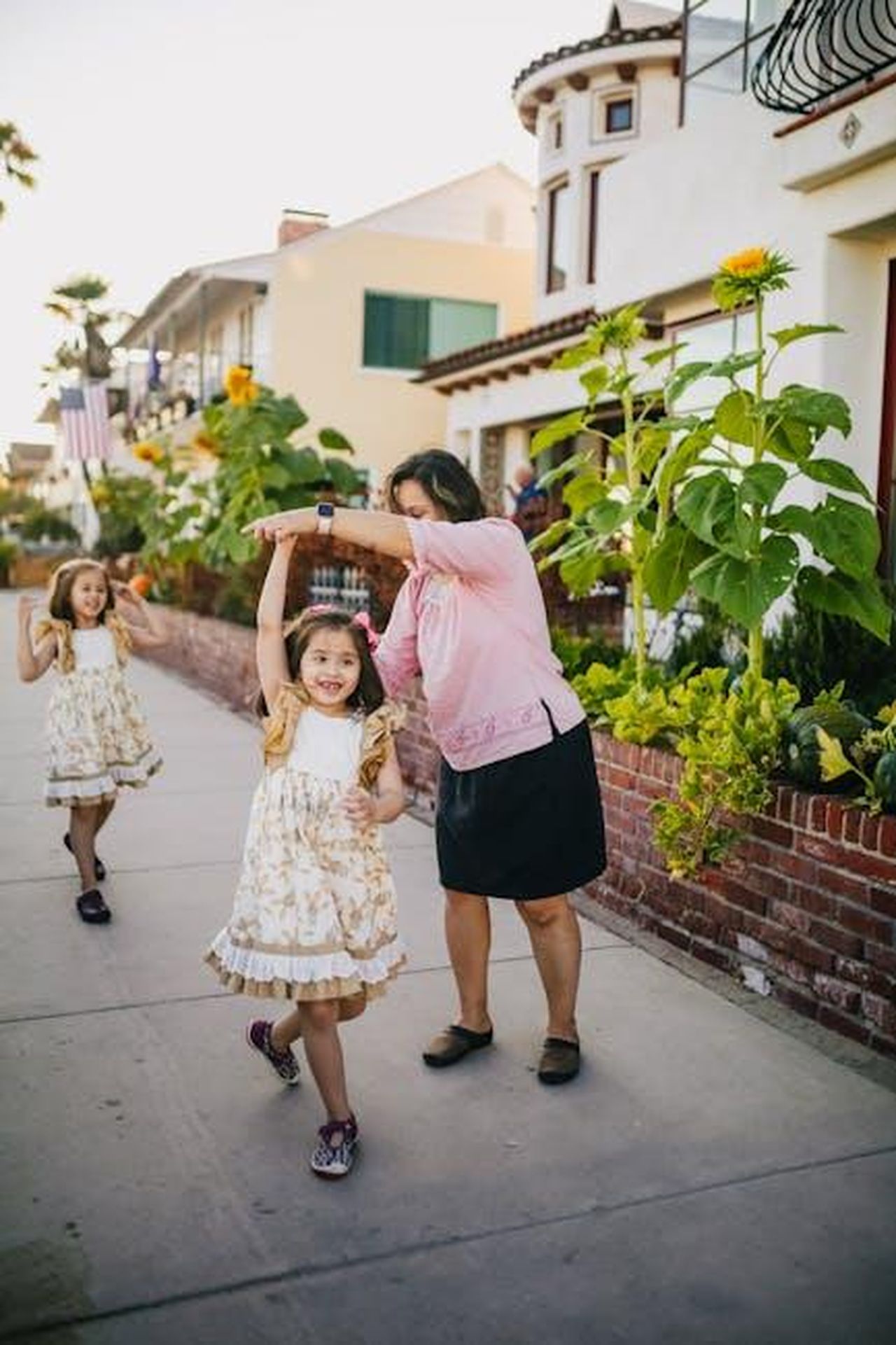 Miranda_Hope__una_mamma_single_di_due_figli_FNxw41Cw5c - Confidenze24 Source: RDNE Stock project - pexels - A mother dances with her daughters on a colorful residential street, enjoying a sunny day outdoors.