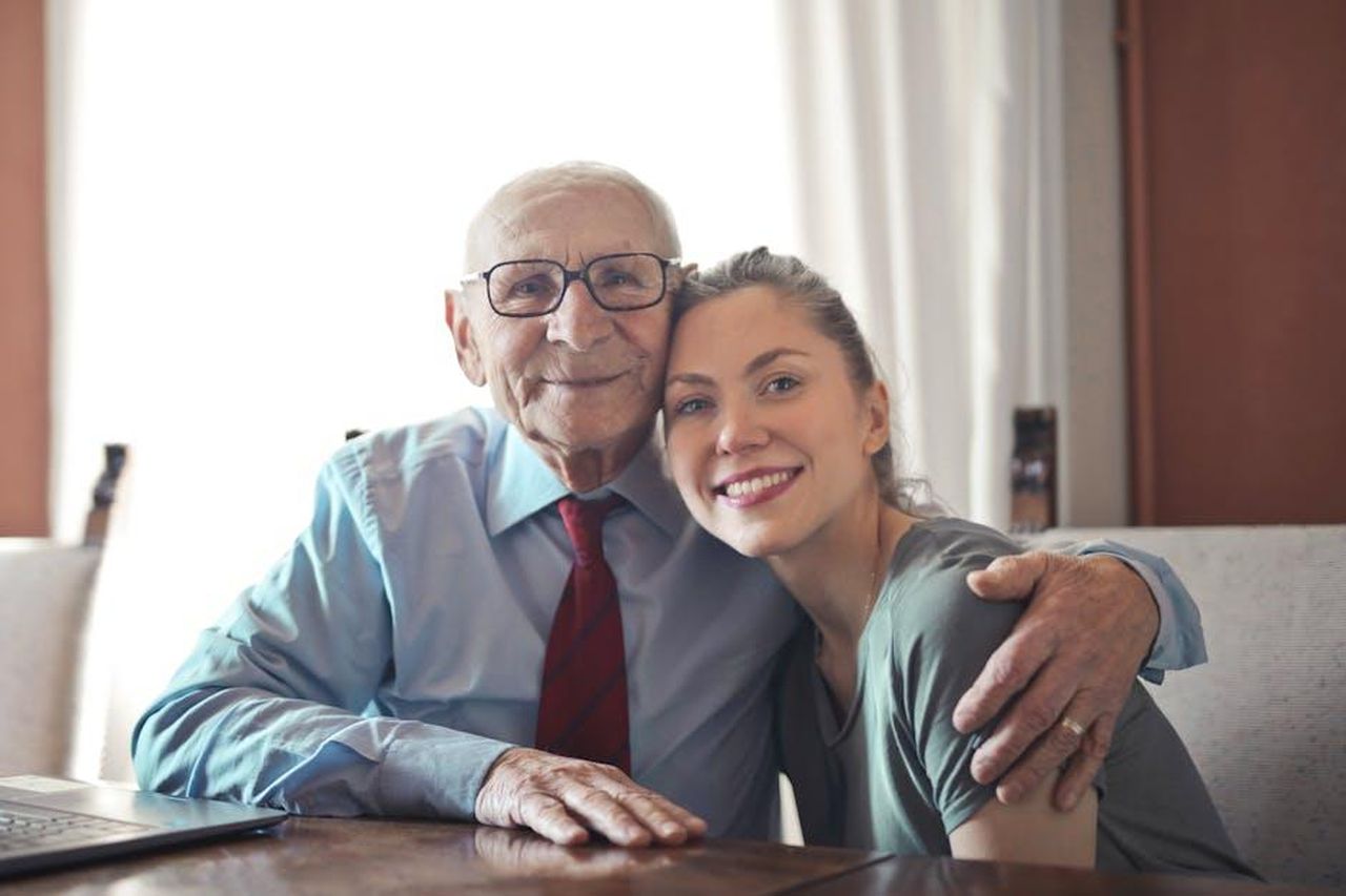 Momenti_affettuosi_tra_Bruce_e_Louetta_pXGoxDEade - Confidenze24 Source: Andrea Piacquadio - pexels - A joyful elderly man and young woman sharing an affectionate embrace indoors.