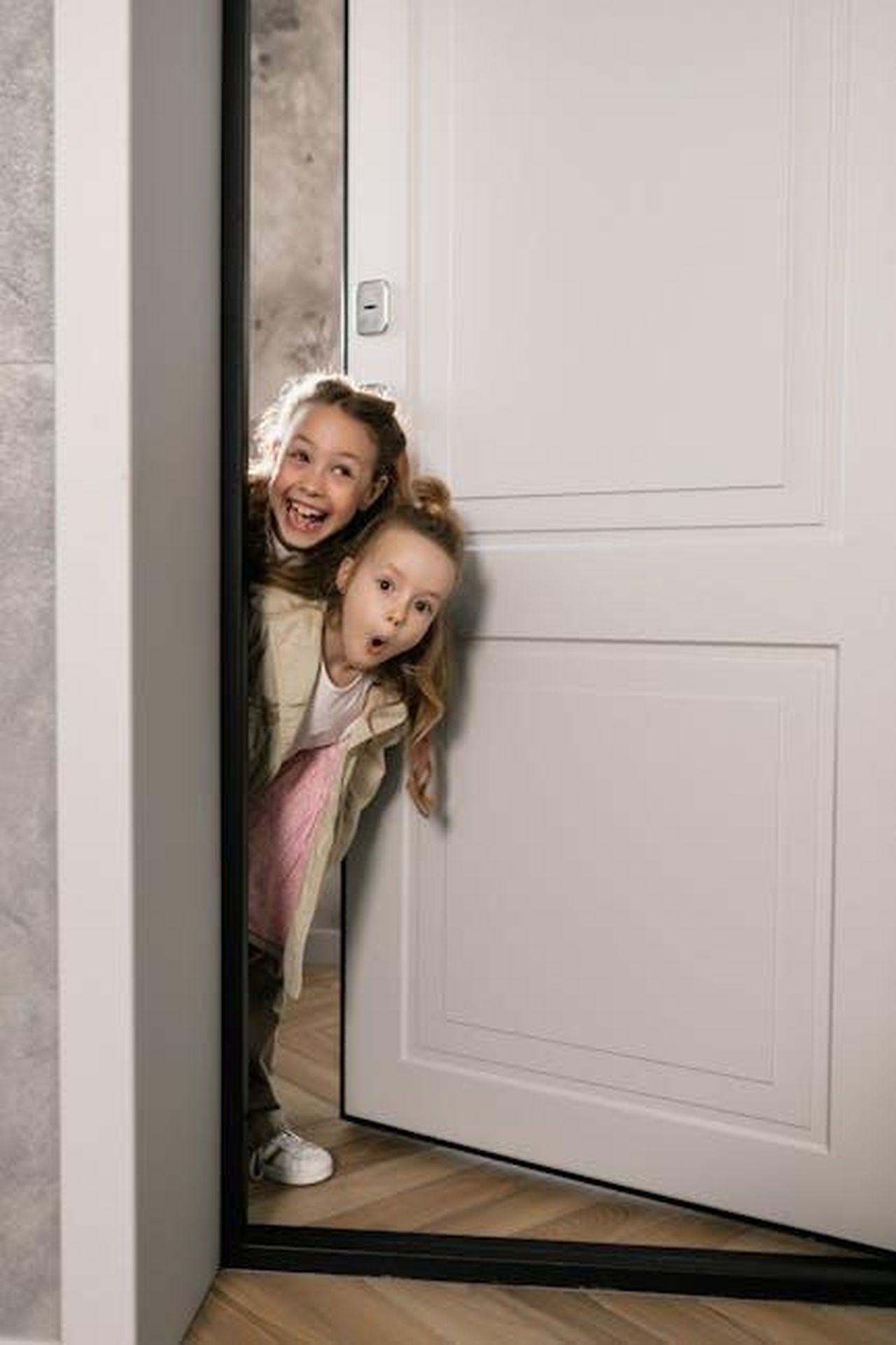 Momenti_divertenti_con_i_figli_TCoJNDzqfD - Confidenze24 Source: Alena Darmel - pexels - Two young girls happily play peekaboo through a door. Perfect for family and childhood themes.