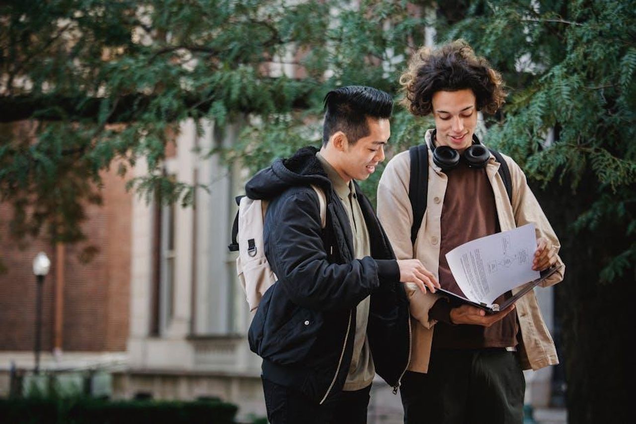 Momenti_salienti_dellintervista_3BwwyDJ5yu - Confidenze24 Source: Armin Rimoldi - pexels - Two diverse university students collaborate on a project outdoors, exchanging ideas and information.