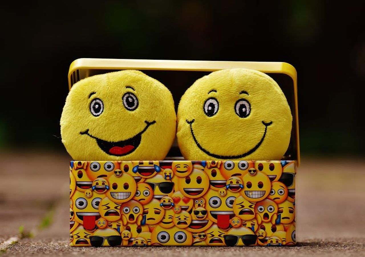 Moss_condivide_le_emozioni_di_essere_madre_sul_set_qRqA1kO5PB - Confidenze24 Source: Pixabay - pexels - Two yellow smiley plush toys in an emoji-themed box, expressing fun and happiness.