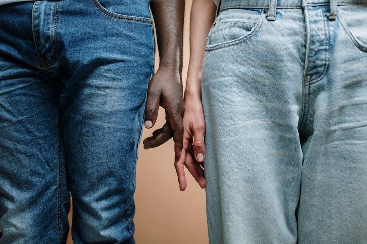 Motivi_della_separazione_xWBr7ES9j0 - Confidenze24 Source: cottonbro studio - pexels - Close-up of an interracial couple holding hands, showcasing unity and diversity in denim jeans.