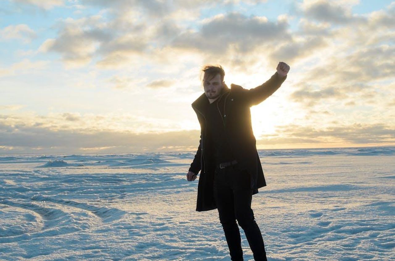 Nessuna_decisione__stata_presa_62pENp98zg - Confidenze24 Source: Ilya Dudnikov - pexels - A man in a coat dances on a snowy landscape with the sun rising behind him, creating a serene winter scene.