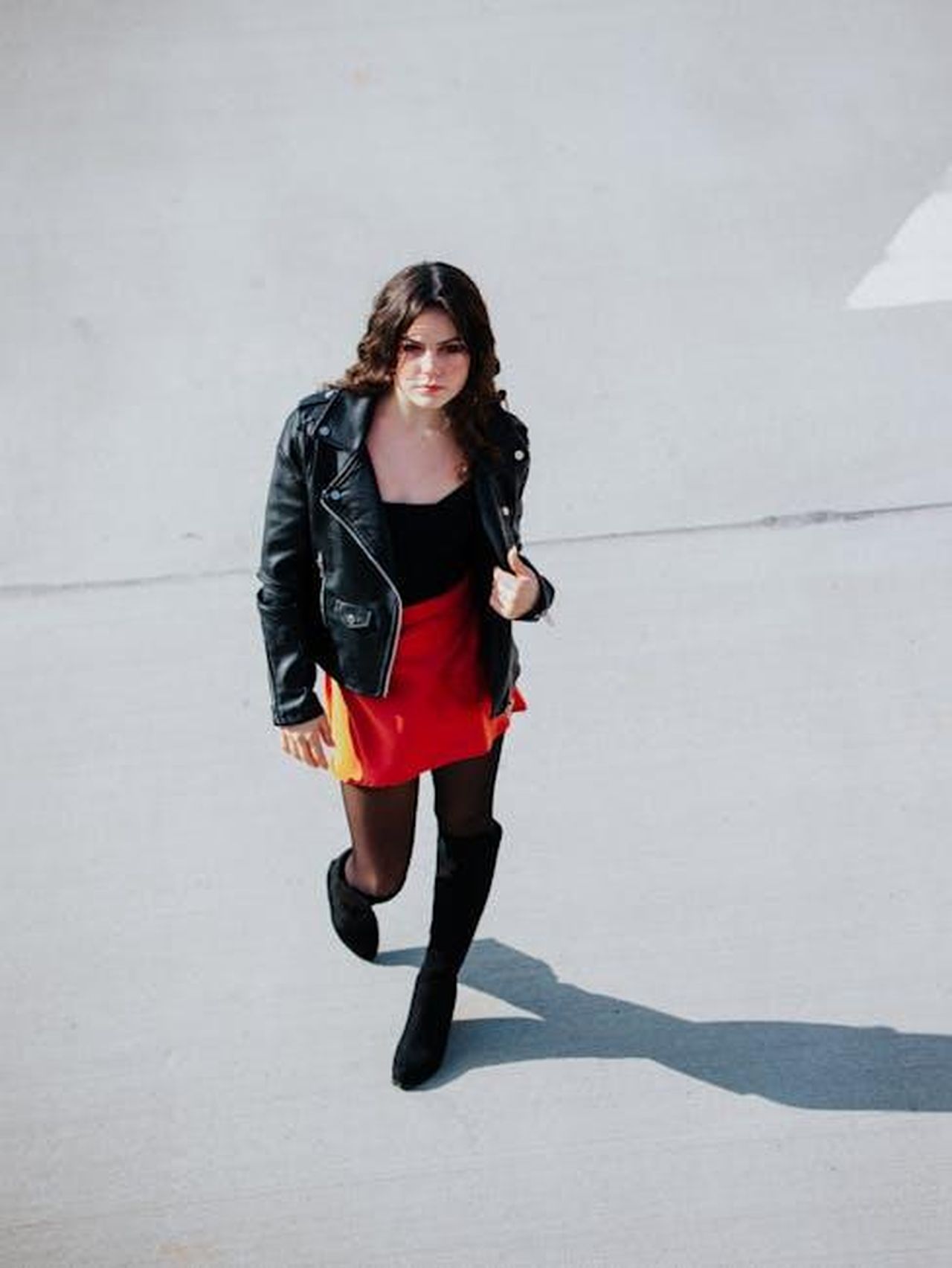 Nomi_trendy_femminili_che_iniziano_con_E_XJmmAfpyoT - Confidenze24 Source: Sherman Trotz - pexels - Chic young woman in red skirt and black jacket walking outdoors in bright daylight.