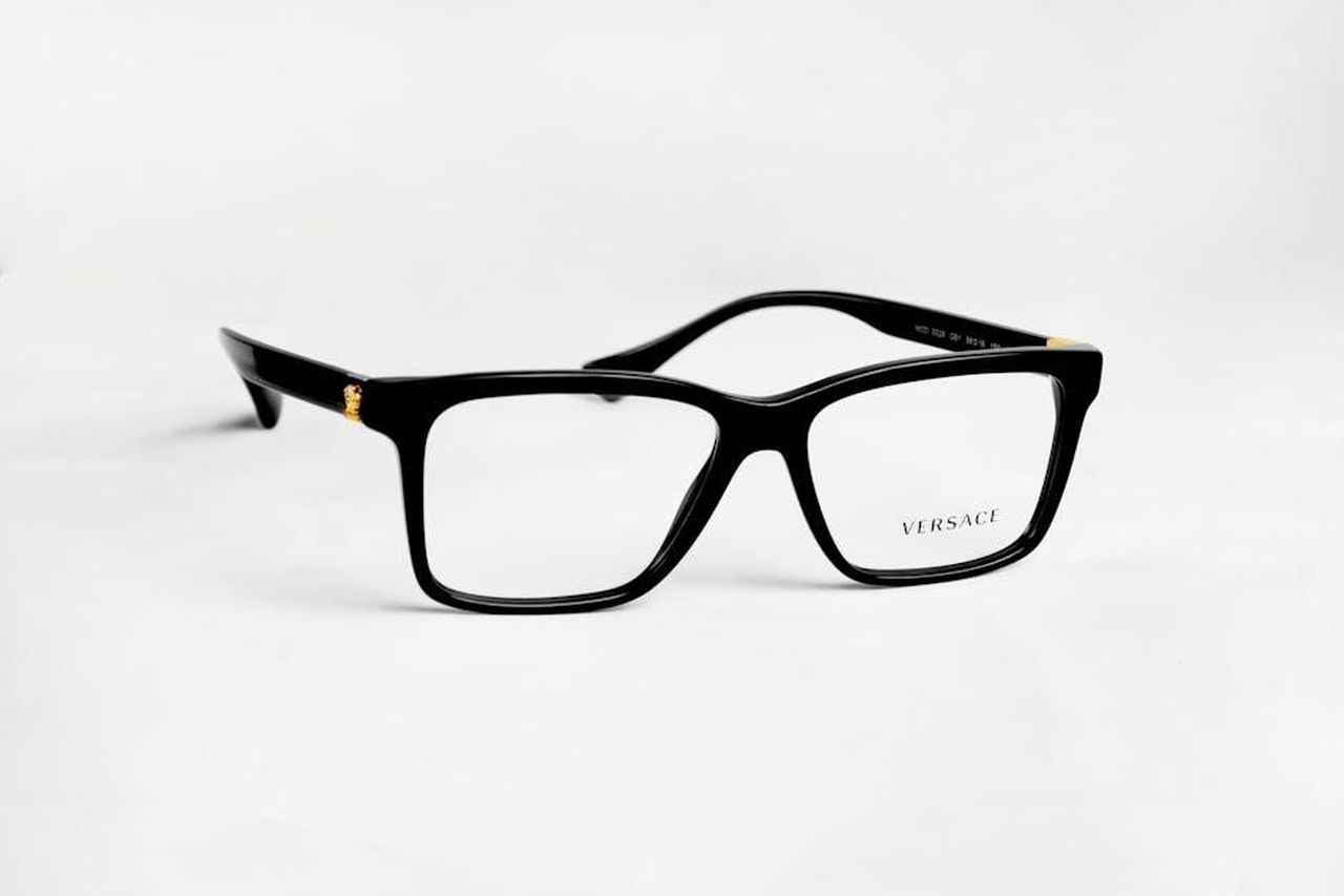 Nomi_unisex_che_iniziano_con_E_xlu2xEm3US - Confidenze24 Source: Joseph Okon - pexels - Close-up of stylish black Versace eyeglasses with gold accents on a white background.