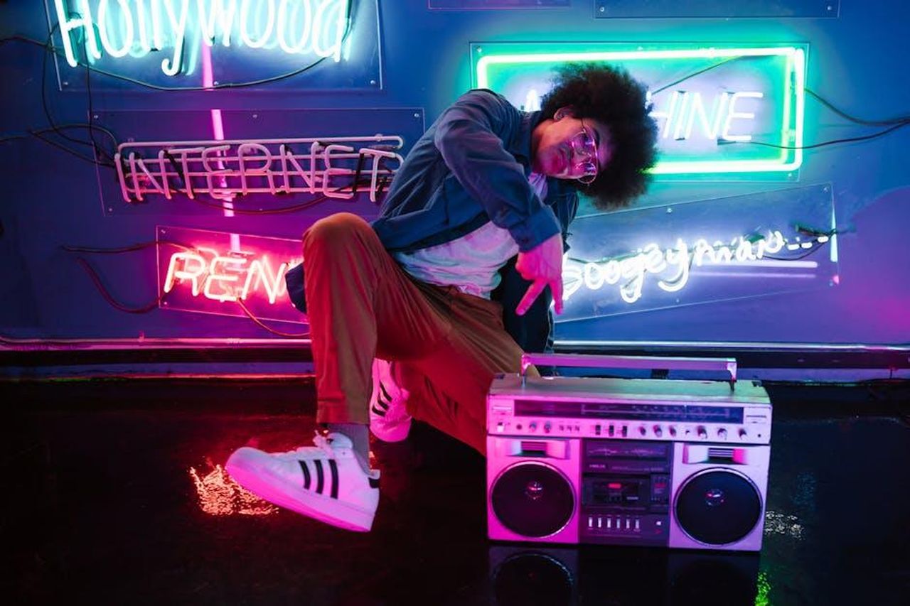 Nostalgia_degli_anni_90_con_Rum_Raisin_sLhSzRphe3 - Confidenze24 Source: RDNE Stock project - pexels - Stylish man poses with a retro boombox in a vibrant neon-lit club scene, evoking a cool nightlife vibe.
