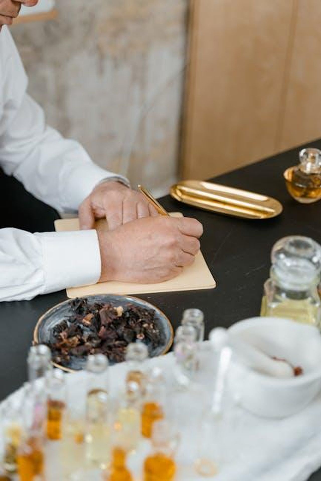 Note_del_profumo_cosa_aspettarsi_da_AlRehab_Choco_Musk_o6S1yyon6m - Confidenze24 Source: MART PRODUCTION - pexels - Aromatherapist writing notes surrounded by natural essential oils and herbs in a calming spa environment.