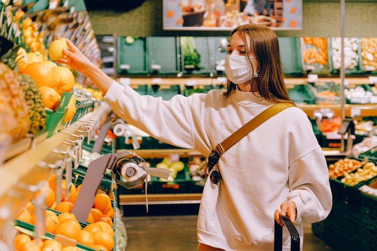 Nuovi_Prodotti_e_Collaborazioni_Esclusive_VmY2wca4Ws - Confidenze24 Source: Anna Shvets - pexels - Woman wearing a mask selecting fruit at a grocery store during pandemic.