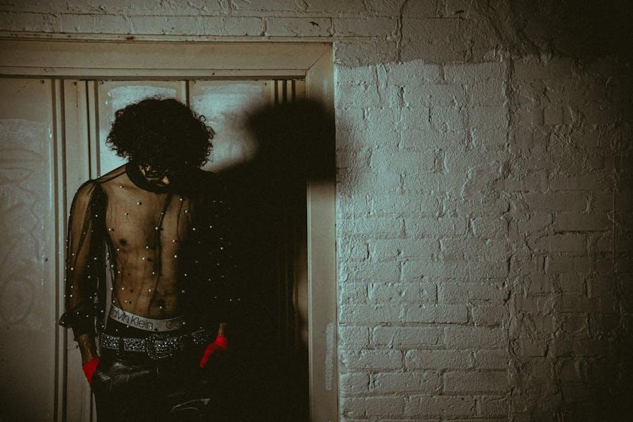 Nuovo_personaggio_introdotto_Randy_11YR6LPvr3 - Confidenze24 Source: Connor McManus - pexels - Fashion model with curly hair in stylish outfit posing indoors with dramatic lighting.