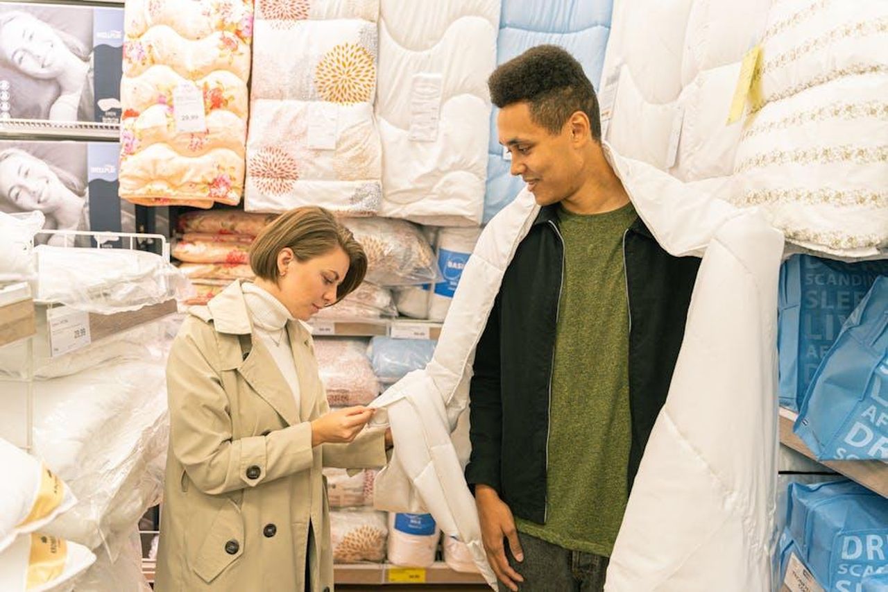 Offerta_imperdibile_su_Amazon_gFKPzvZQYB - Confidenze24 Source: Antoni Shkraba - pexels - A man and woman selecting bedding in a home goods store, browsing quilt options.