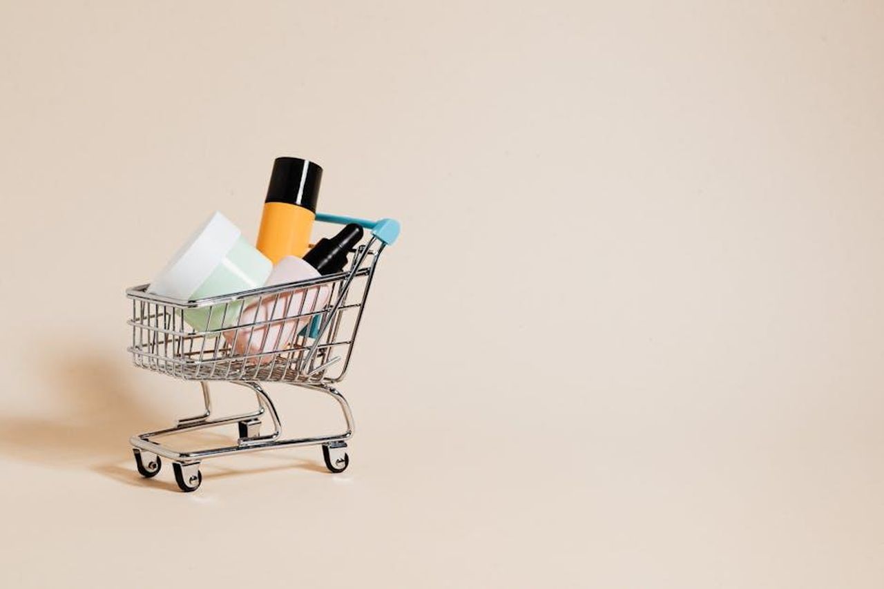 Offerta_speciale_Beauty_Balm_a_met_prezzo_QuT7vGO9f7 - Confidenze24 Source: Photo By: Kaboompics.com - pexels - A minimalist image of a mini shopping cart filled with cosmetics on a beige background, ideal for e-commerce concepts.