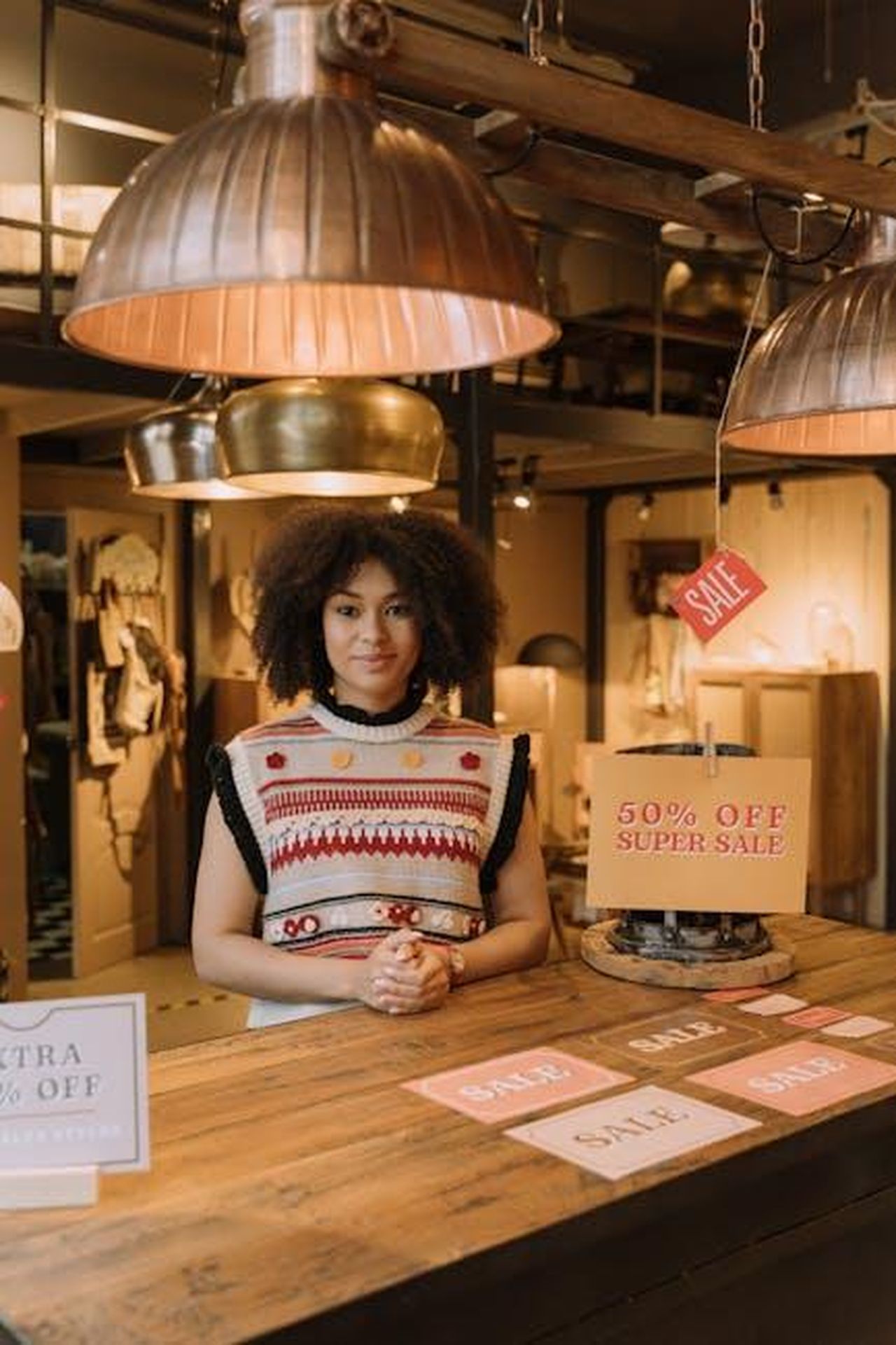 Offerta_speciale_su_Amazon_SWBOv5E0Rw - Confidenze24 Source: cottonbro studio - pexels - Fashionable store setting with afro-textured hair model showcasing sale signs on a wooden table.