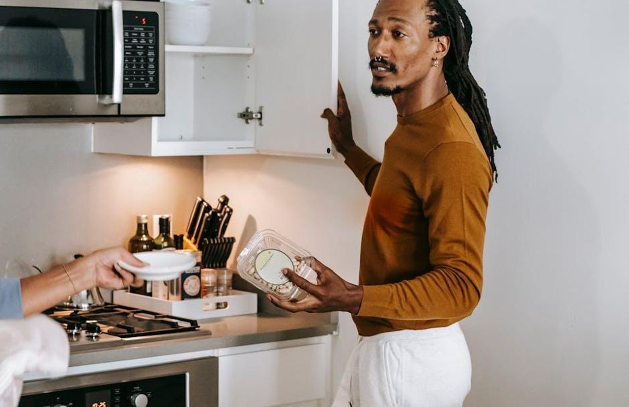 Opinioni_alimentari_e_momenti_di_riflessione_di_Dylan_JV5cAZFW4L - Confidenze24 Source: Alex Green - pexels - Black male and faceless female in casual outfit talking in kitchen while standing near shelves in daylight