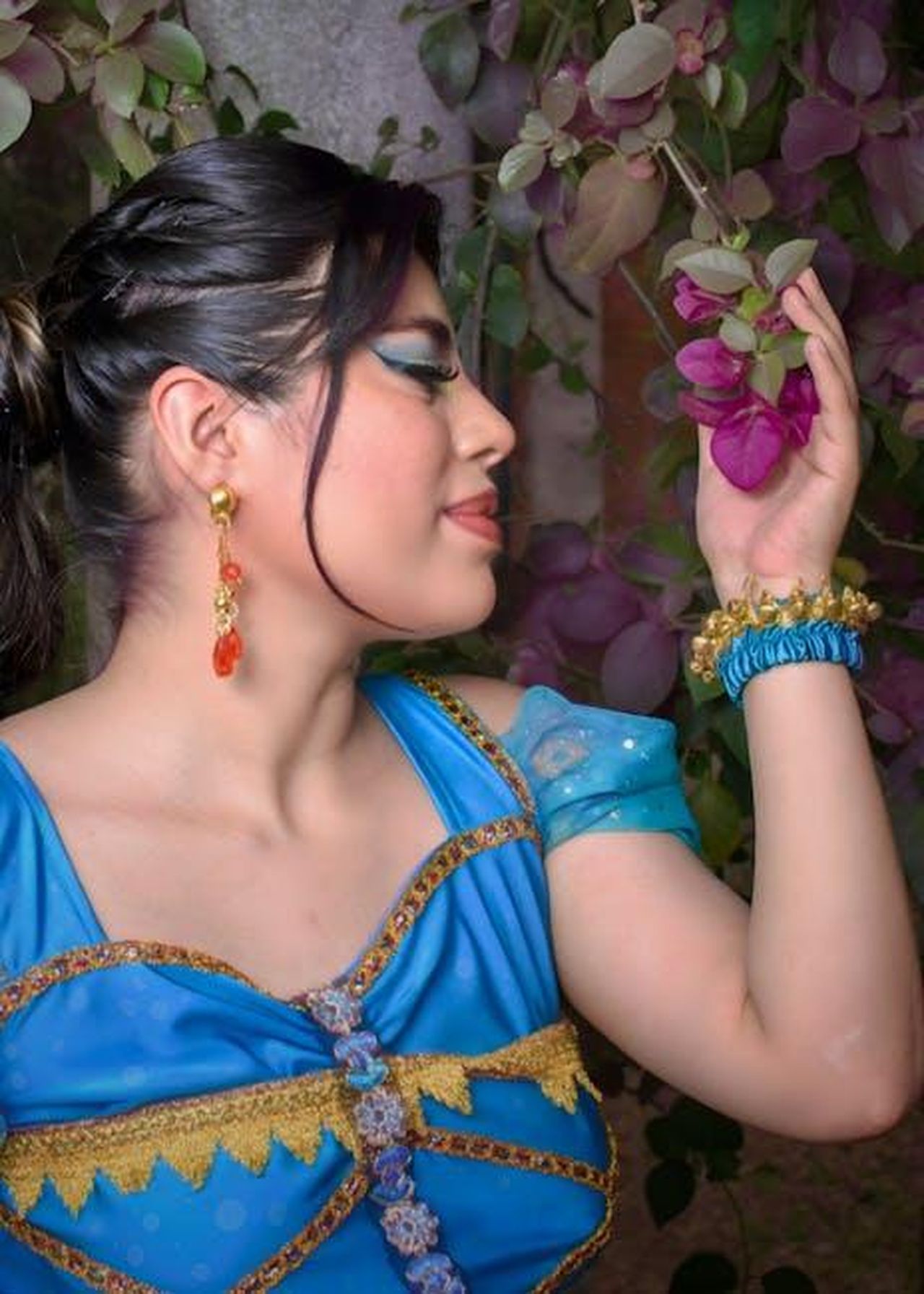 Orecchini_Disney_accessori_che_fanno_colpo_KAZI39YAFp - Confidenze24 Source: Angel Rkaoz - pexels - Woman in vibrant princess costume admiring colorful flowers on a warm day.