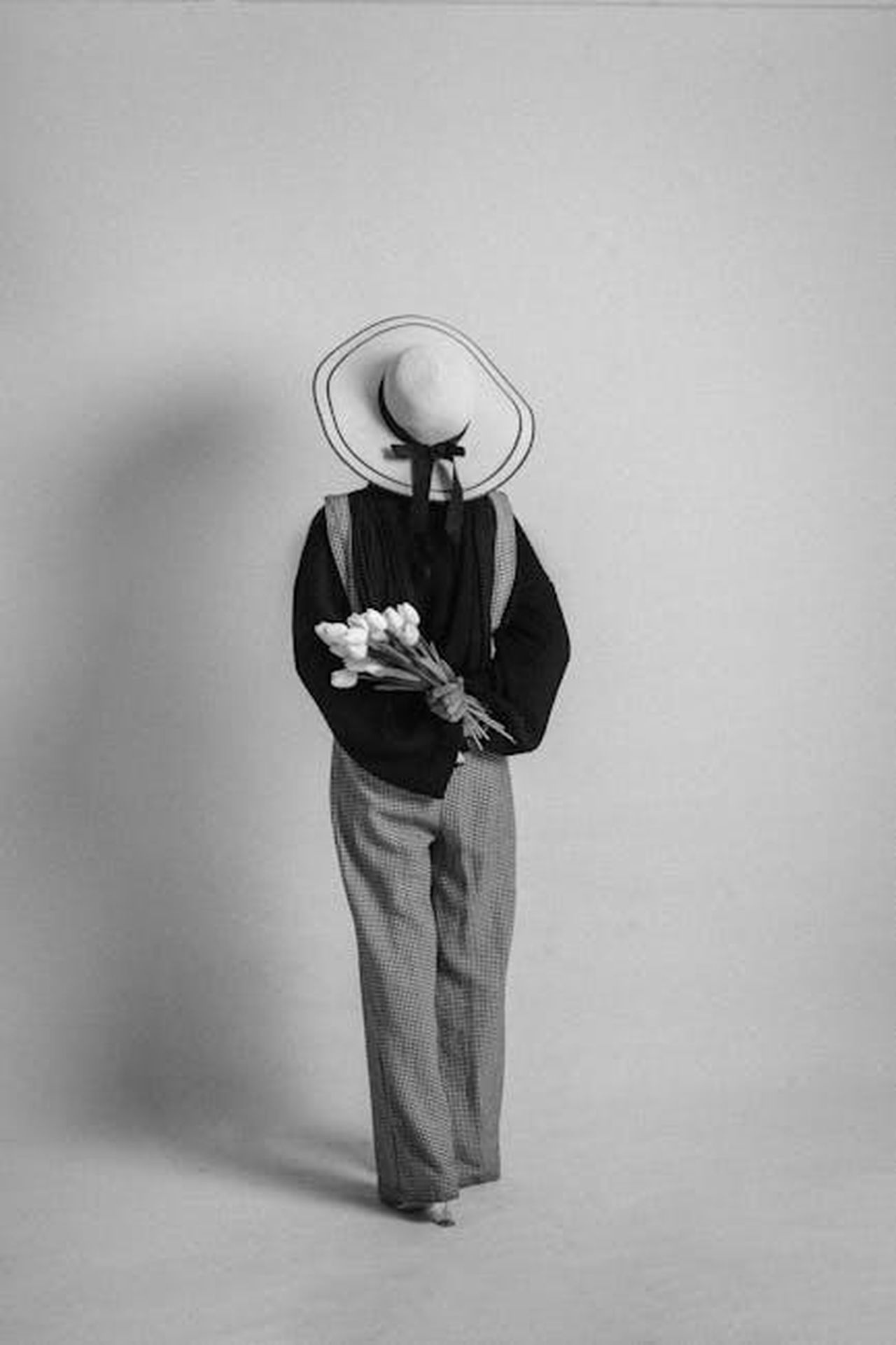 Pantaloni_classici_in_crepe_stretch_KGpZujWz7I - Confidenze24 Source: casper somia - pexels - Monochrome portrait of a woman holding tulips, wearing a stylish outfit and hat.